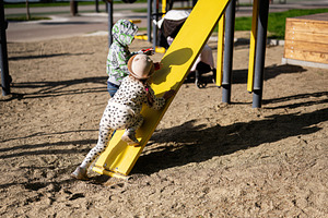 Children playing on a playground slide on a sunny day, a Person Photo by AS photostudio