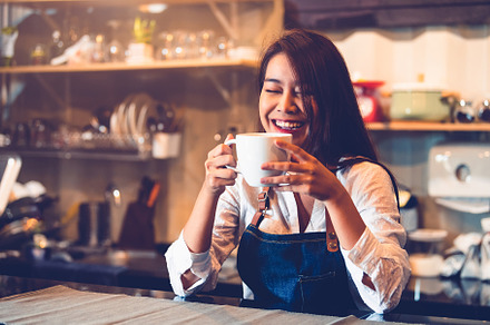 Happy Asian female barista holding cup of coffee and tasting bre, a Person Photo by Ministocker