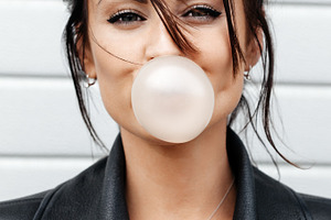 Beautiful young woman blowing a bubble gum balloon