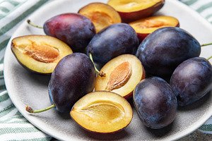 Fresh ripe plums with halves on plate for healthy eating, a Food & Drink Photo by Olena Rudo