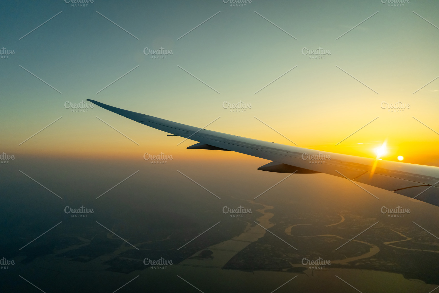 Airplane wing above Osaka coast during sunset descent flight, a Nature Photo by GoodGoods