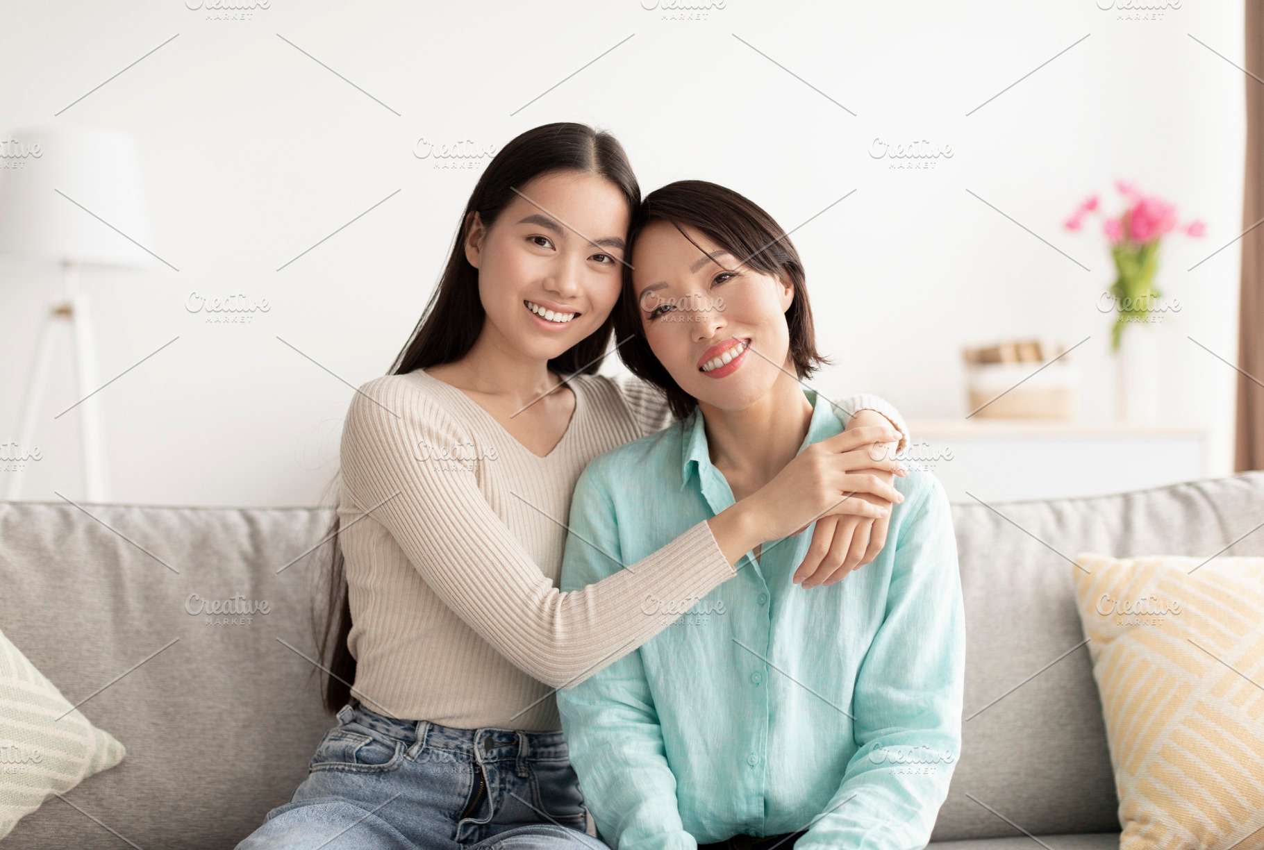 Portrait of young Asian woman and her mature mother hugging and smiling at came, a Photo by Prostock-Studio