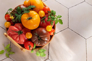 Heirloom tomatoes in basket showing harvest freshness, a Food & Drink Photo by Olena Rudo