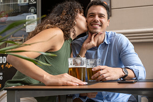 Happy Young Man Kissing His Girlfriend on the Cheek at an Outdoor Cafe, a Person Photo by etorres69