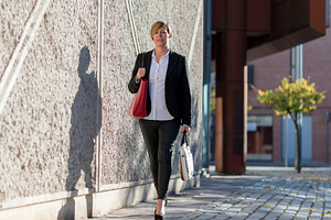 Businesswoman walking outdoors with handbags, a Photo by RF Images