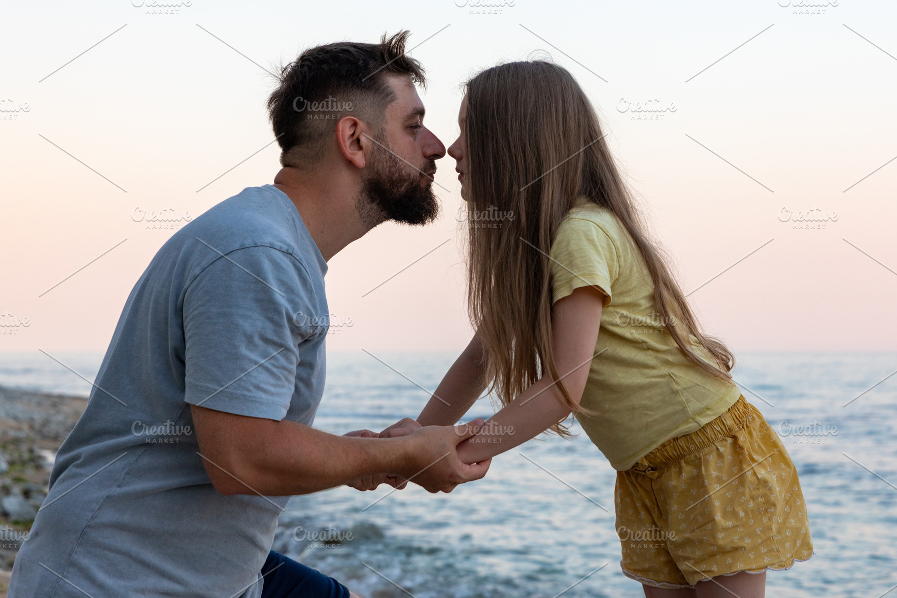 Father and daughter share a sweet moment by the seaside at sunset, holding hand, a Person Photo by Ales Munt