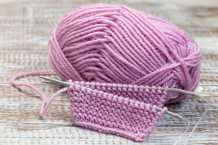 Knitting with needles and pink yarn skein on wooden background, horizontal, an Arts & Entertainment Photo by iuliia_n