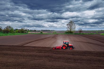 A red tractor working in the field. Agricultural red small tractor in the field