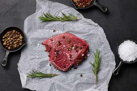 Raw piece of beef with spices lies on a white piece of parchment, a Food & Drink Photo by ndanko
