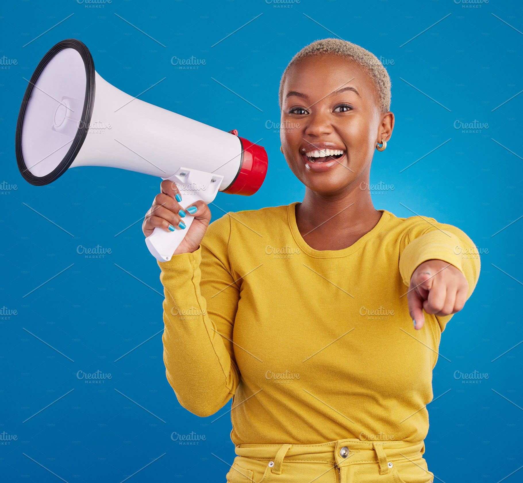 Black woman, megaphone and pointing, protest and voice, freedom of speech and activism on blue background. Happy female, broadcast and speak out, rally and portrait, loudspeaker and opinion in studio, a Photo by Peopleimages.com