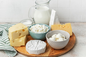 Assortment of fresh dairy products on wooden board, a Food & Drink Photo by Olena Rudo