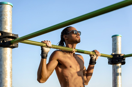 Man doing pull-ups on bar outdoors, a Sports & Recreation Photo by Perpis