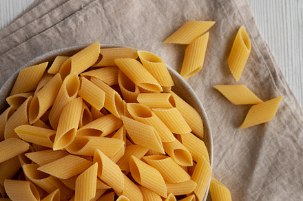 Raw Organic Dry Pennoni Pasta in a Bowl, top view. Copy space., a Food & Drink Photo by LiudmylaChuhunova
