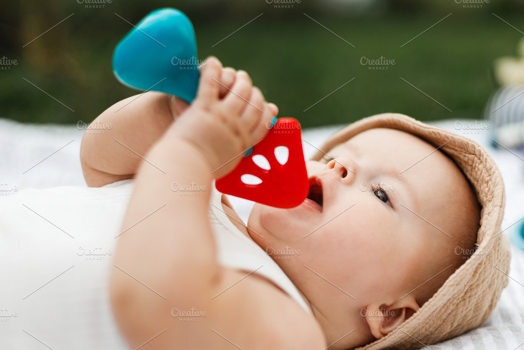 Beautiful happy baby in hat lying on blanket and playing with te, a Person Photo by Sonjachni