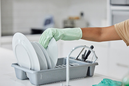 Woman hand, plate dishes and sink in kitchen for washing, cleaning and hygiene in house chores with gloves. Cleaner lady, hand and home for clean, stop bacteria and service for wellness in apartment, a Photo by Peopleimages.com