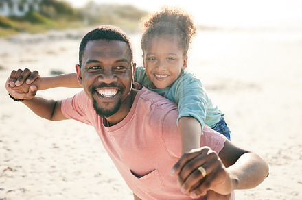 Black family, beach and a piggyback daughter with her father outdoor in nature together during summer. Portrait, smile or fun with a happy dad and girl child bonding on the sand by the ocean or sea, a Photo by Peopleimages.com