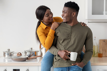 Romantic Young African American Couple Hugging And Drinking Coffee In Kitchen I, a Photo by Prostock-Studio