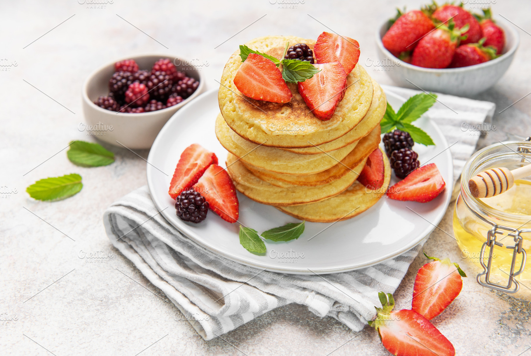 Stack of pancakes with fresh berries and honey, a Food & Drink Photo by Olena Rudo