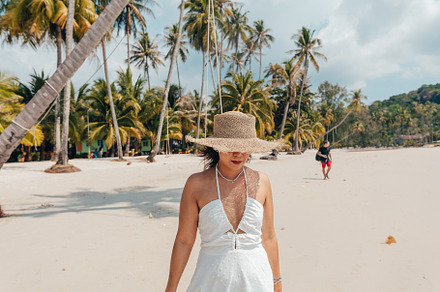 A woman in a hat enjoys the summer sun on a beautiful tropical b, a Holiday Photo by Art Rachen