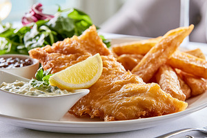 Crispy golden fish and chips served on a white plate with fresh salad greens, l, a Photo by Studio ANNA