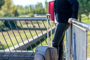 Businesswoman with suitcase standing on bridge, a Photo by RF Images