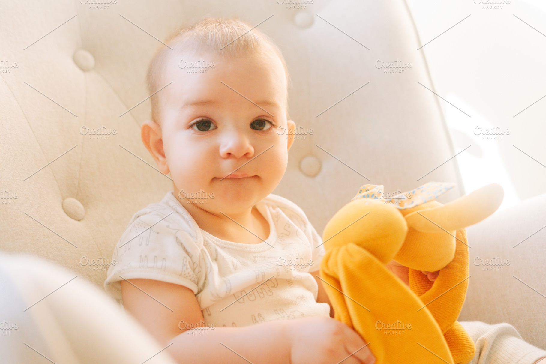 Portrait of a nine month old baby with a stuffed bunny sitting in a rocking cha, a Person Photo by rubenchase
