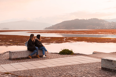 Two female friends sitting on a bench, a Person Photo by rubenchase