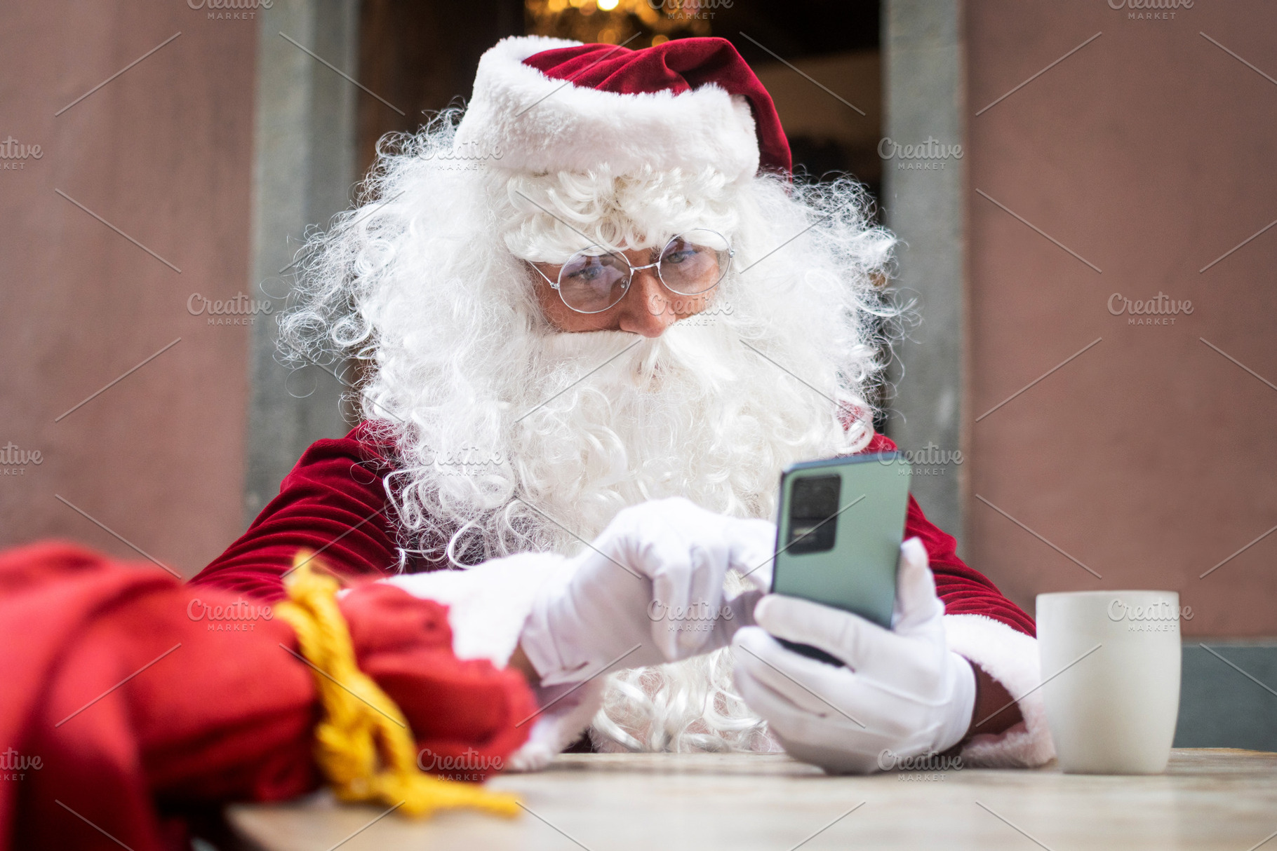 Santa Claus using smartphone during coffee break at cafe, a Holiday Photo by etorres69
