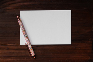 Blank white card with floral pen on wooden background, creating a ready to writ, a Photo by Studio ANNA