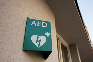 Green AED sign on wall indicating defibrillator location, a Photo by AS photostudio