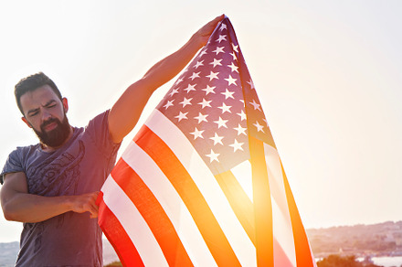 Man holding big waving USA flag, a Person Photo by Kira Yan