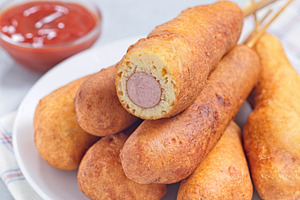 Corn dogs on white plate, served with ketchup, horizontal closeup, a Food & Drink Photo by iuliia_n
