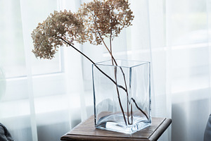 Glass vase with dried hydrangea flowers on wooden stool by windo, an Industrial Photo by MDBildes