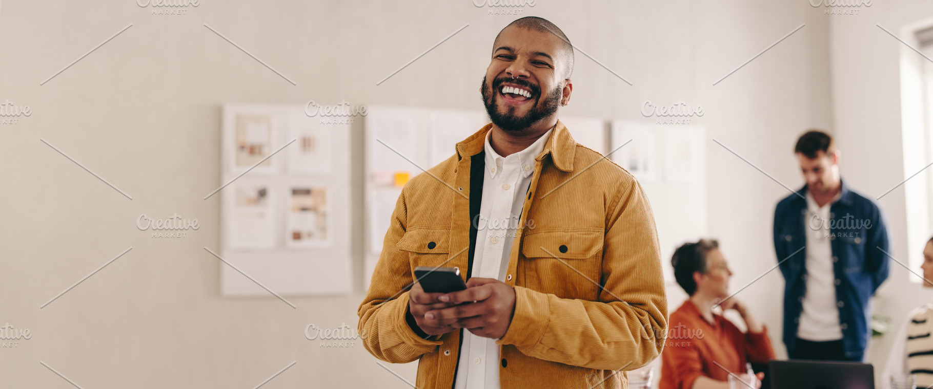 Modern businessman smiling at the camera while holding a smartph, a Person Photo by Jacob Lund
