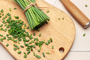 Freshly cut chives on wooden cutting board with knife, a Food & Drink Photo by Olena Rudo