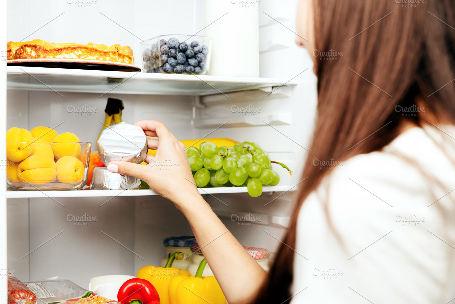 Hand taking, picks up camembert or brie cheese out of open refrigerator, fridge, a Food & Drink Photo by Lenor4ik