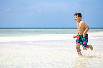 Little kid running on a white sand beach, a Person Photo by Cosca