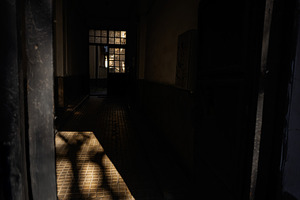 Dimly lit hallway with sunlight and shadows in an urban building, a Photo by AS photostudio
