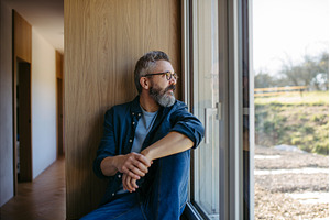 Middle aged man sitting by window, a Person Photo by HalfPoint