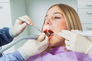 Dentist using dental drill on female patient in clinic, a Health & Medical Photo by Antonio Gravante Market