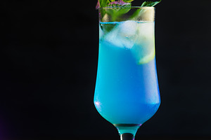 Blue lagoon cocktail with lemon slice and mint leaves.