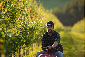 Farmer sitting on small tractor in, a Business Photo by HalfPoint