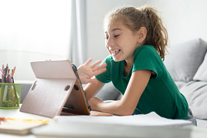 Happy girl waving during video call on tablet, a Person Photo by etorres69