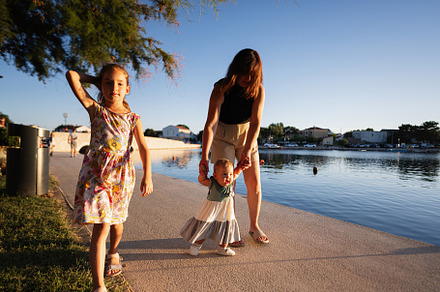 Mother and two young daughters walking along a sunny waterfront in Nin, Croatia, a Person Photo by AS photostudio