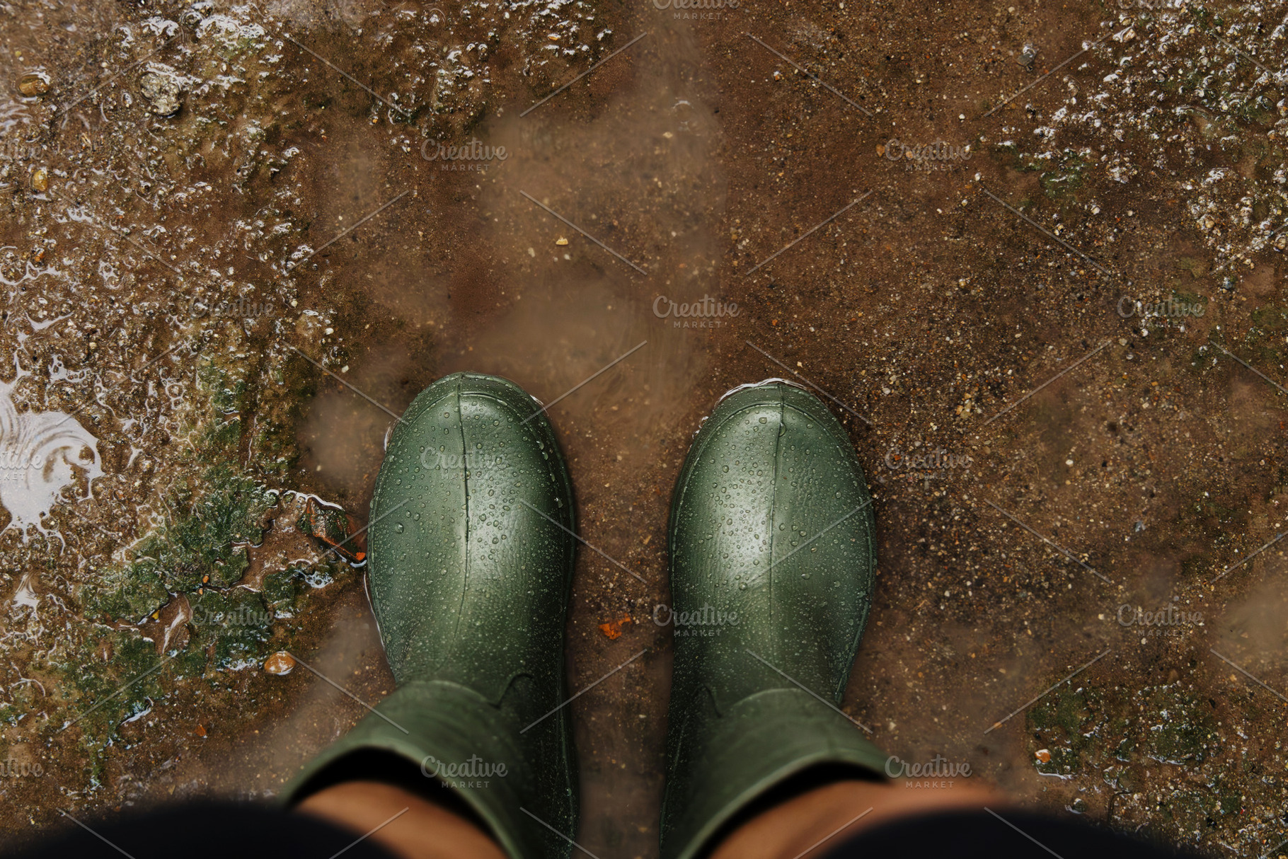 POV shot of person with rain boots standing on wet ground during, a Photo by salmon.black