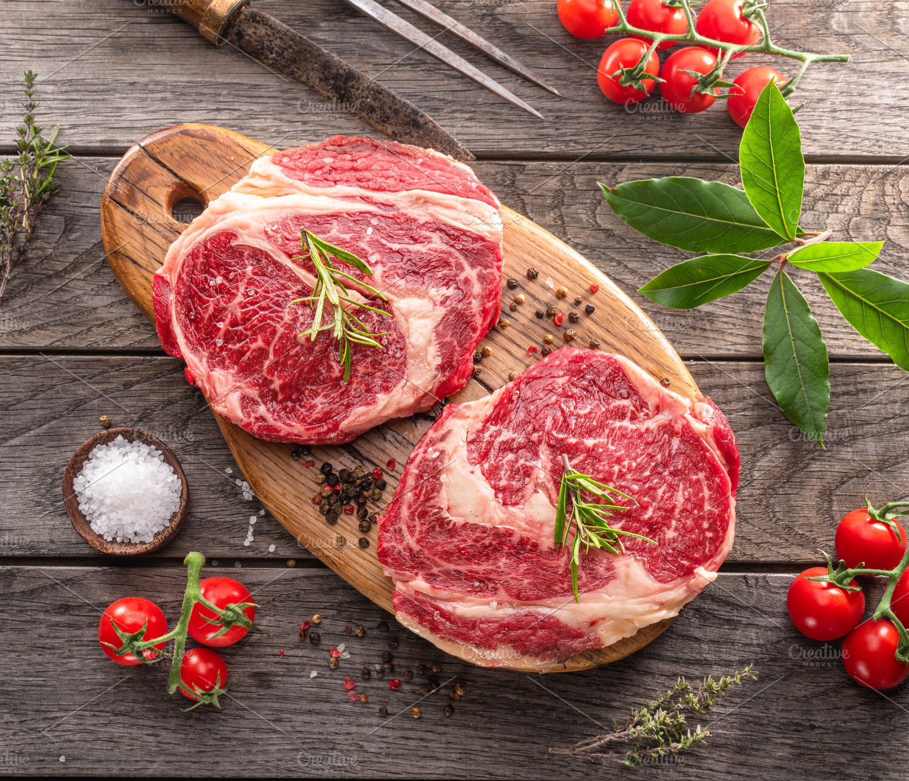 Raw beef steaks with herbs and spices ready for cooking are on w, a Food & Drink Photo by Volff