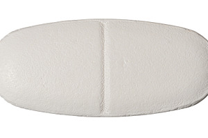 Close-up of a white oval tablet with a score line, isolated back