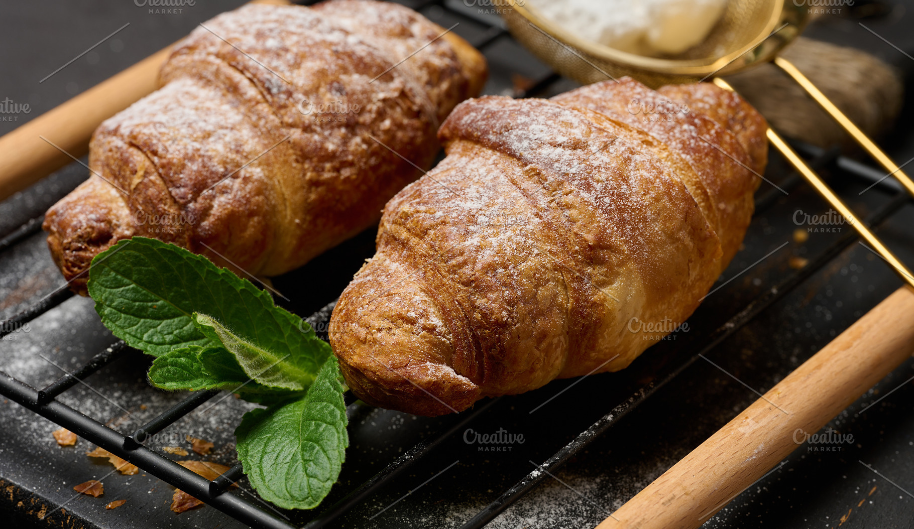 Baked croissants sprinkled with powdered sugar on a metal rack,, a Food & Drink Photo by ndanko