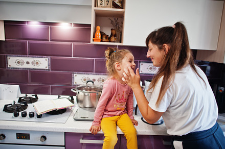 Mother with daughter cooking at kitchen, happy children's moment, a Person Photo by AS photostudio