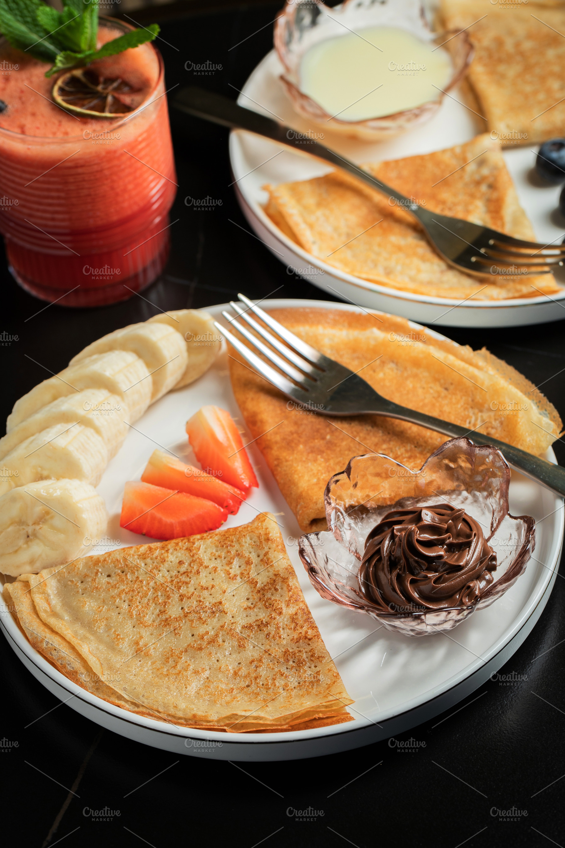 A plate of crepes filled with chocolate spread and topped with b, a Food & Drink Photo by Budarinphoto